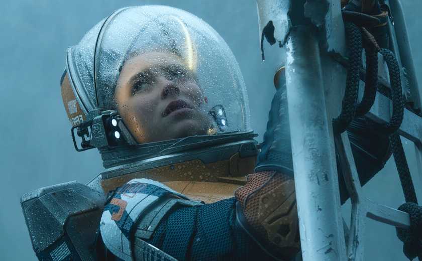 A woman in a retro glass and leather spacesuit climbs a ladder in Lost in Space